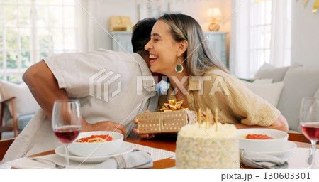 Birthday cake, whisper and gift with couple, love and date together in home living room with drink. Happy, smile and people at table with conversation and celebration dessert with alcohol and talking 130603301