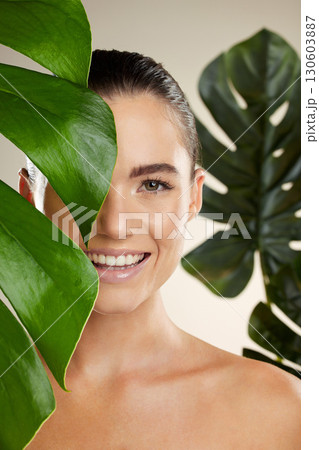 Woman, beauty and skincare portrait with plant for natural skin dermatology or cosmetic product. Happy face aesthetic model in studio for sustainable self care with green leaf for health and wellness Woman, beauty and skincare portrait with plant for natural skin dermatology or cosmetic product. Happy face aesthetic model in studio for sustainable self care with green leaf for health and wellness 130603887
