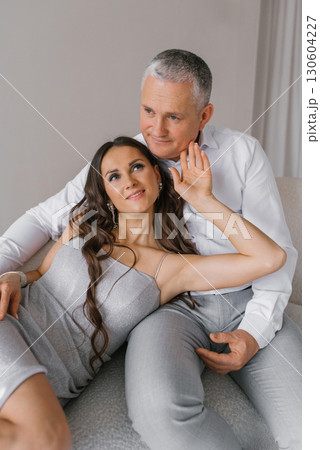 Couple in love is sitting on white sofa and hugging Couple in love is sitting on white sofa and hugging 130604227
