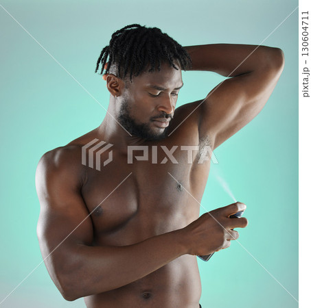 Body hygiene and black man with deodorant spray product for self care routine of people in studio. Health, wellness and cosmetic grooming of person with skincare at isolated green background. Body hygiene and black man with deodorant spray product for self care routine of people in studio. Health, wellness and cosmetic grooming of person with skincare at isolated green background. 130604711