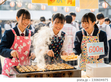 文化祭で賑わう高校の校庭、笑顔でたこ焼きを作る女子高生たち 130604975