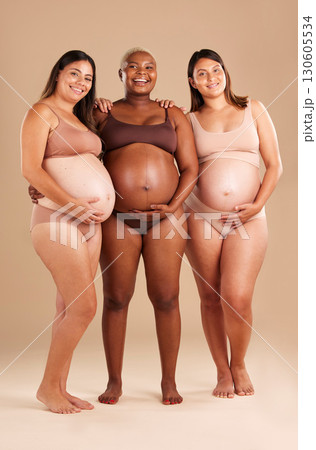 Pregnant, body and portrait of women in stomach support touch, hope and community diversity on studio background. Smile, happy and pregnancy friends in underwear, belly growth and healthcare wellness 130605534