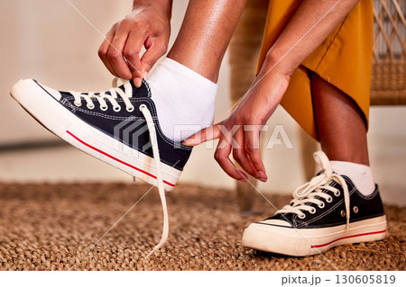 Hands, shoes and lace getting ready for walk, travel or shopping on the carpet floor or mat at home. Hand of person tying laces, fitting or putting on shoe in preparation for walking, journey or trip 130605819