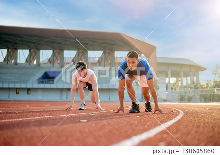 Two asian men in a set position ready to run on the racetrack. Outdoor exercise, Athlete training. Two asian men in a set position ready to run on the racetrack. Outdoor exercise, Athlete training. 130605860