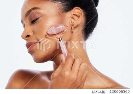 Facial roller, beauty and face of a woman in studio for dermatology, cosmetics and natural skin. Aesthetic model person with facial massage tools for healthy glow isolated on a white background Facial roller, beauty and face of a woman in studio for dermatology, cosmetics and natural skin. Aesthetic model person with facial massage tools for healthy glow isolated on a white background 130606560