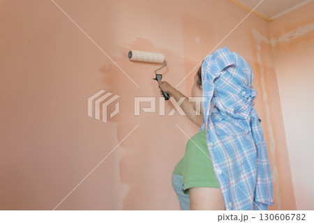 Person Painting Peach Wall Interior with Roller, Home Renovation, DIY Project, Light Blue Shirt, Neutral Colors, Bright Room, Sunlight, Casual Style Person Painting Peach Wall Interior with Roller, Home Renovation, DIY Project, Light Blue Shirt, Neutral Colors, Bright Room, Sunlight, Casual Style 130606782