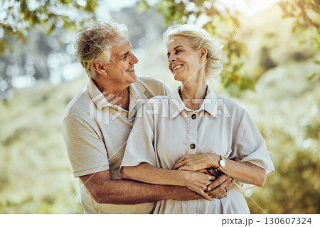 Love, hug or old couple in a park or nature bonding or holding hands in a happy marriage partnership. Retirement, senior man or romantic elderly woman hugging together in a relaxing holiday vacation 130607324