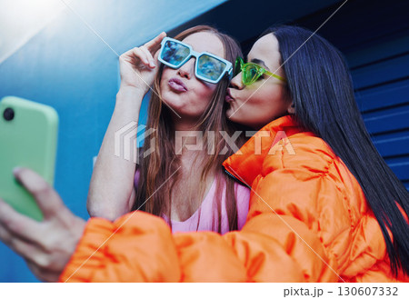 Selfie, fashion and friends with smartphone on blue background with style, cool sunglasses and urban clothes. Social media, freedom and women smile for photo on weekend, vacation and holiday in city Selfie, fashion and friends with smartphone on blue background with style, cool sunglasses and urban clothes. Social media, freedom and women smile for photo on weekend, vacation and holiday in city 130607332