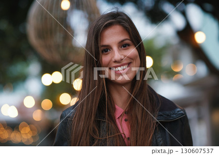Portrait, smile and happy with a woman outdoor in the city during the evening on a blurred background. Face, holiday and travel with an attractive young female tourist standing out on the town 130607537