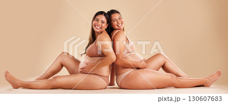 Pregnant woman friends, studio and underwear with smile, sitting and together for support by backdrop. Happy women, pregnancy and solidarity for wellness, care and holding healthy stomach by backdrop 130607683