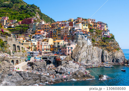 Multicolor houses on cliff edge. Manarola Italian village Cinque Terre, Liguria, Italy. Summer sea Multicolor houses on cliff edge. Manarola Italian village Cinque Terre, Liguria, Italy. Summer sea 130608080