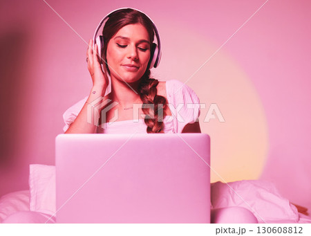 Pink, light and laptop by woman in a bed with music, social media and streaming on wall background. Podcast, website and girl relax in bedroom, happy and enjoying radio, audio or online playlist 130608812