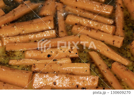 Close up of honey roasted carrots batons in oil cooking 130609270