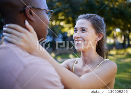 Interracial love, couple and park for date, summer holiday and outdoor wellness with hug, care and commitment. Happy, young and diversity people in a green garden, nature and natural fun together 130609296