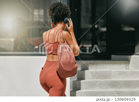 Fitness, headphones or personal trainer walking to gym listening to music to start a workout, exercise or training. Sports girl, back view or healthy black woman traveling or streaming radio audio Fitness, headphones or personal trainer walking to gym listening to music to start a workout, exercise or training. Sports girl, back view or healthy black woman traveling or streaming radio audio 130609329