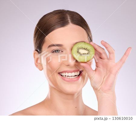 Woman, face and hand with kiwi for skincare nutrition or healthy diet against gray a studio background. Portrait of happy female smile with fruit for organic facial treatment or natural cosmetics Woman, face and hand with kiwi for skincare nutrition or healthy diet against gray a studio background. Portrait of happy female smile with fruit for organic facial treatment or natural cosmetics 130610010