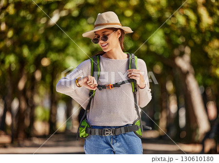 Woman, backpack and checking watch in nature travel, sightseeing or adventure in park, trees forest or Canada woods. Smile, happy and tourist on time clock for gps, location map or hiking technology 130610180