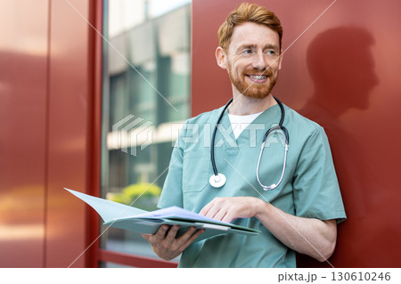 Male healthcare worker in scrubs holding open folder Male healthcare worker in scrubs holding open folder 130610246