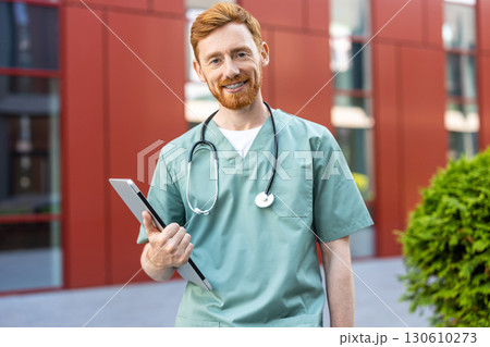 Young adult man medic standing confidently with closed laptop 130610273