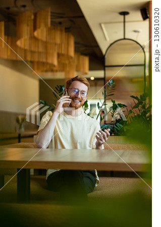 Red-haired man communicating on phone in cozy cafe 130610320