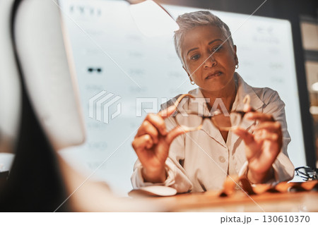 Glasses, optometry and check with a mature woman optician looking at a pair of frame spectacles in the office. Eyewear, healthcare and examine with a female optometrist checking prescription lenses Glasses, optometry and check with a mature woman optician looking at a pair of frame spectacles in the office. Eyewear, healthcare and examine with a female optometrist checking prescription lenses 130610370