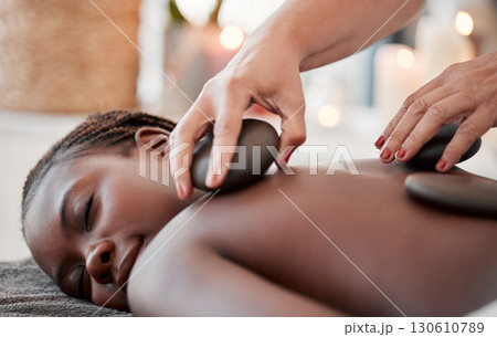 Black woman, hot stone massage, spa and hands of masseuse, holistic and wellness, therapy and treatment. Health, peace of mind and rocks with zen, stress relief for people and back skin detox Black woman, hot stone massage, spa and hands of masseuse, holistic and wellness, therapy and treatment. Health, peace of mind and rocks with zen, stress relief for people and back skin detox 130610789