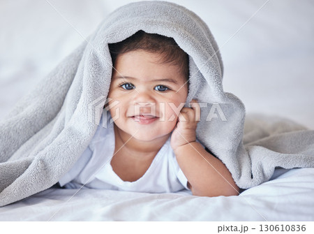 Happy, comfy and portrait of a baby on a bed to relax, sleep and rest with a blanket. Smile, cute and adorable girl child lying in the bedroom for relaxation, comfort and happiness in a house 130610836
