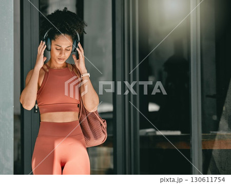 Fitness, walking and black woman listen to music, relax podcast or radio for calm, stress relief or wellness mockup. Headphones, leaving gym and mock up girl on travel after training workout exercise 130611754
