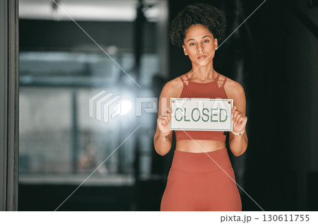 Fitness, portrait or personal trainer at gym with a closed sign for workout exercises or training. Manager, bankruptcy or serious black woman holding a board to stop exercising in empty health club Fitness, portrait or personal trainer at gym with a closed sign for workout exercises or training. Manager, bankruptcy or serious black woman holding a board to stop exercising in empty health club 130611755