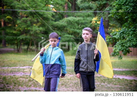 flags of Ukraine in hands of two boys. Children hold Ukrainian flags yellow and blue waving in wind . Ukraine's Independence Day. Flag Day 130611951