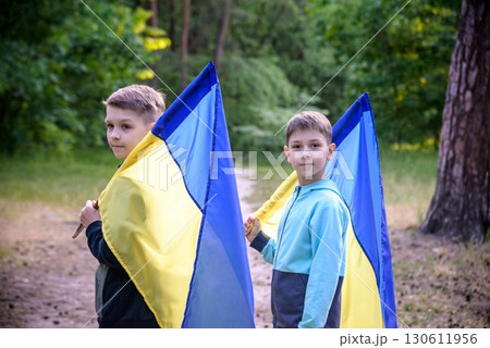 flags of Ukraine in hands of two boys. Children hold Ukrainian flags yellow and blue waving in wind . Ukraine's Independence Day. Flag Day 130611956
