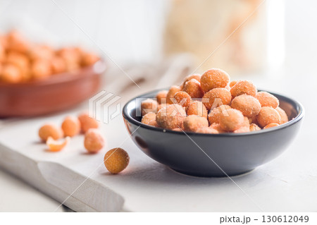 Peanuts in a crispy crust in bowl on white table. Peanuts in a crispy crust in bowl on white table. 130612049