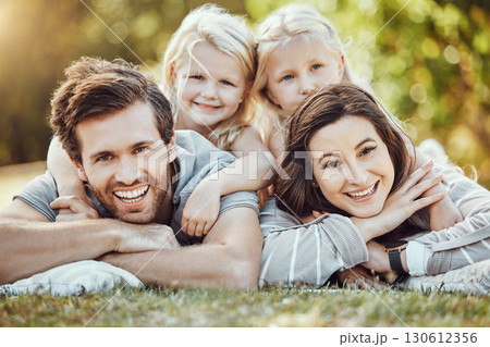 Family, park and outdoor portrait of parents and girl children with love and care in nature. Mother, dad and kids with a smile in summer feeling happy on green grass bonding together on a picnic 130612356