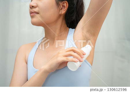 Asian young woman applying roll on deodorant reduce underarm sweat and odor after shower. Asian young woman applying roll on deodorant reduce underarm sweat and odor after shower. 130612596