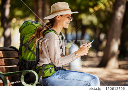 Woman, backpack or phone in travel, sightseeing or adventure in nature park, trees forest or Canada woods. Smile, happy or tourist on mobile technology for gps map, location or hiking path research 130612796