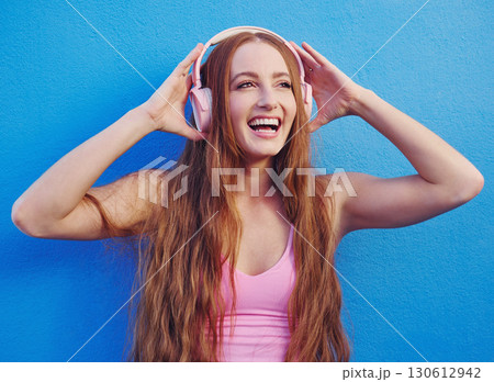 Music, headphones and blue background with a woman streaming or listening to audio for fun. Radio, internet and 5g with an attractive young female using wireless technology to listen to a song Music, headphones and blue background with a woman streaming or listening to audio for fun. Radio, internet and 5g with an attractive young female using wireless technology to listen to a song 130612942