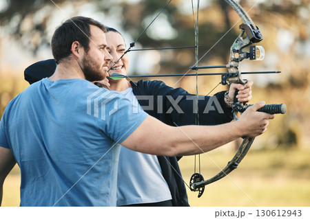 Archery, bow and shooting range sports training with a woman and man outdoor for target practice. Archer and athlete person with focus on field for competition or game to aim arrow for action 130612943