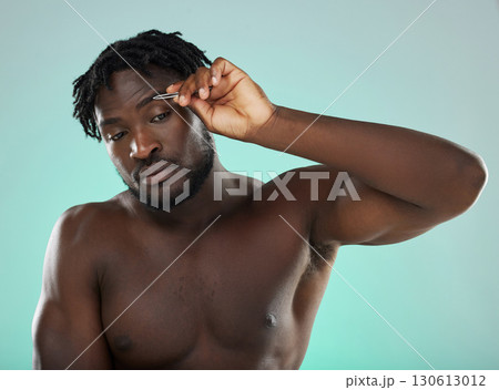 Black man, studio and tweezer for eyebrows, cosmetic beauty and grooming by blue background for wellness. Model, cosmetic and facial hair removal with metal tools for aesthetic, cleaning or self care Black man, studio and tweezer for eyebrows, cosmetic beauty and grooming by blue background for wellness. Model, cosmetic and facial hair removal with metal tools for aesthetic, cleaning or self care 130613012