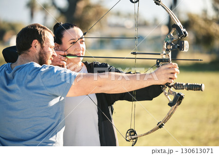 Archery, aim and shooting range sports training with a woman and man outdoor for target practice. Archer and athlete person with focus on field for competition or game with bow and arrow for action Archery, aim and shooting range sports training with a woman and man outdoor for target practice. Archer and athlete person with focus on field for competition or game with bow and arrow for action 130613071