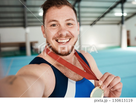 Gymnastics, fitness and male athlete taking a selfie after winning a medal in competition. Sports, smile and portrait of happy male gymnast winner taking a picture after training or practice in arena 130613119