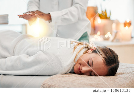 Relax, reiki and woman on bed at spa for chakra therapy with light energy and holistic medicine. Spiritual healing, balance and zen, person with peaceful and healthy mindset at traditional massage. 130613123