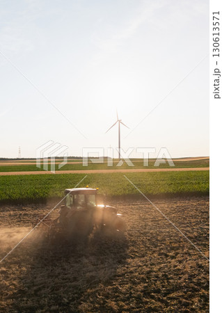 Agricultural tractor is working on the field with wind turbines. Aerial view. Agricultural tractor is working on the field with wind turbines. Aerial view. 130613571