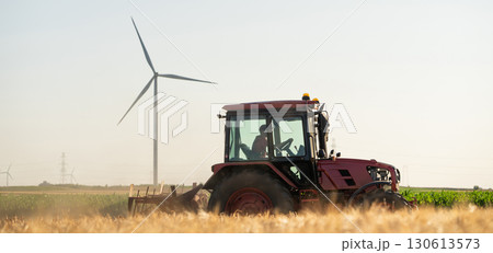 Agricultural tractor is working on the field with wind turbines Agricultural tractor is working on the field with wind turbines 130613573