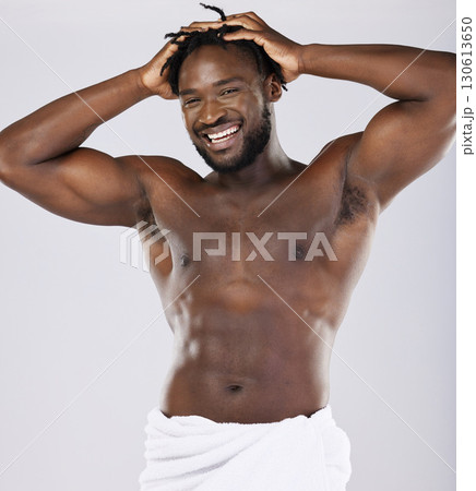 Black man in towel and skin in portrait, shower and hygiene, grooming and beauty isolated on studio background. Smile, muscle and abs, strong and skincare glow, body care with natural cosmetics 130613650