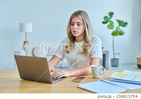 Young woman university student sitting at desk with laptop, typing writing studying 130613754