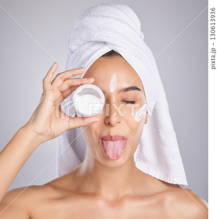 Woman, skincare cream and tongue in studio for wellness, health and cosmetic health with towel by background. Young healthy model, lotion and funny face for facial, self care and comic by backdrop 130613936