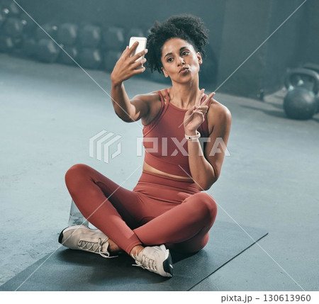Fitness, selfie and woman on a gym floor with phone, peace and hand sign before exercise routine. Workout, picture and peace gesture by black woman posing for photo after training, emoji and relax 130613960