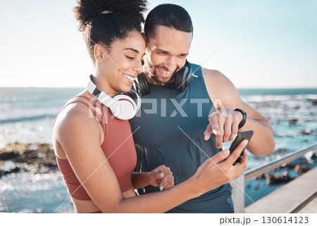 Fitness, couple and phone with smile for social media, communication or discussion relaxing by the beach. Happy man and woman smiling in happiness looking or browsing on smartphone by the ocean coast Fitness, couple and phone with smile for social media, communication or discussion relaxing by the beach. Happy man and woman smiling in happiness looking or browsing on smartphone by the ocean coast 130614123