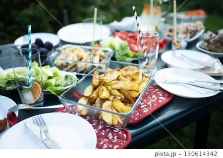 Baked potato wedges served in glass dish on picnic table 130614342