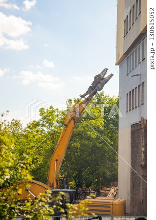 Demolition excavator using hydraulic jaws to dismantle a concrete building at a construction site. Concept of heavy machinery, structural teardown and industrial development. Demolition excavator using hydraulic jaws to dismantle a concrete building at a construction site. Concept of heavy machinery, structural teardown and industrial development. 130615052